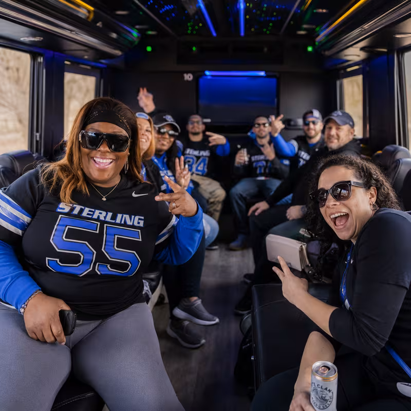 Group boarding a white charter bus for Sporting Event Transportation transportation in Sterling Heights